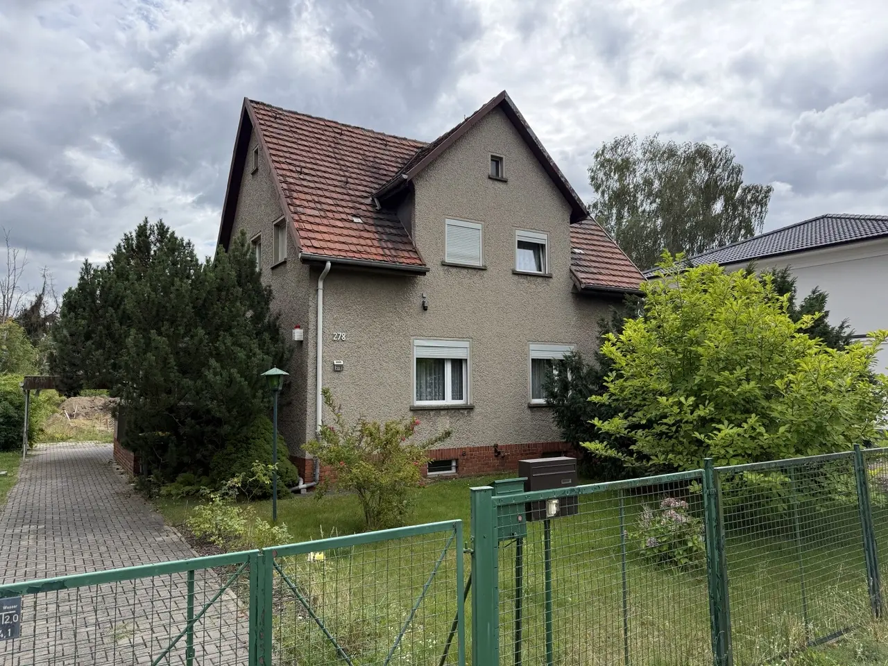 Älteres Siedlungshaus Hönower Straße 278 in Berlin-Mahlsdorf mit großem Grundstück, im Hintergrund ein moderner Neubau als Zeichen der Nachverdichtung